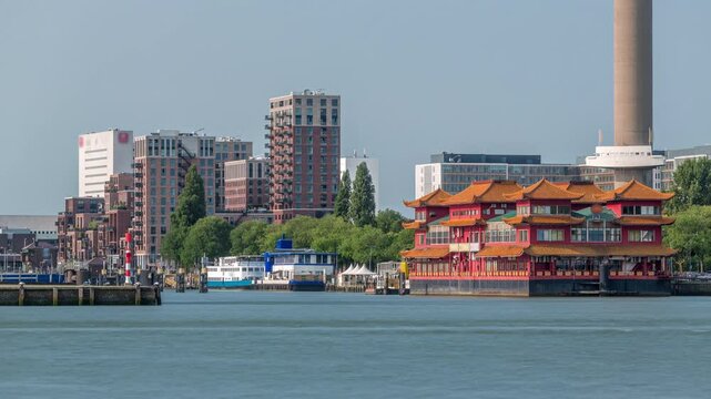 Rotterdam cityscape timelapse near Euromast observation tower and a tourist boat on Nieuwe Maas River. Waterfront features modern skyscrapers, a floating Chinese restaurant and a scenic harbor view