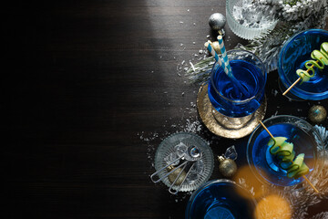 Blue cocktail in glasses, christmas tree branches with snow and balls on wooden background, space for text