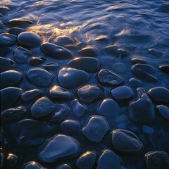 Obraz premium Smooth, glossy stones resting in tranquil waters, reflecting soft sunlight and surrounded by gentle ripples, creating a serene natural atmosphere and perfect for relaxation.