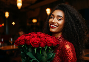 happy young smiling african woman holding red rose bouquet
