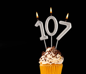 Number 107 shaped candles - Birthday cupcake on black background.