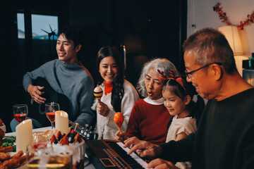 Multi-Generation Family Celebrate Christmas At Home Wearing Santa Hats And Antlers Opening Presents