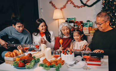 Multi-Generation Family Celebrate Christmas At Home Wearing Santa Hats And Antlers Opening Presents