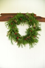 Natural Evergreen Wreath with red berries on White Wood Background