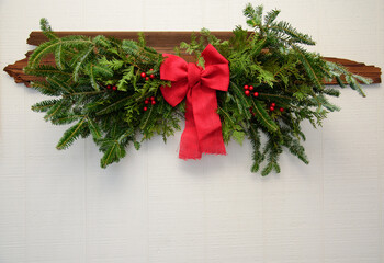 Natural Evergreen Swag Branches with Red bow on White Wood Background