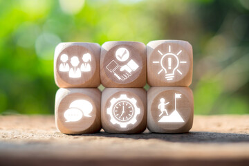 Wooden blocks with icons representing essential soft skills like teamwork, communication, and leadership, set against a blurred natural background.