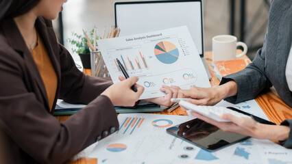 Two business professionals reviewing sales analysis charts and graphs in a modern office environment.