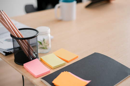A tidy office desk featuring colorful sticky notes, pencils in a holder, and a notebook, ideal for productivity and organization themes.