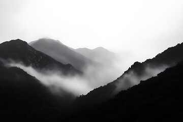 A serene black-and-white landscape of misty mountains shrouded in fog.
