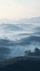 Serene mist-covered hills create a tranquil landscape at dawn.