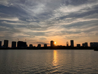 Fototapeta premium City Sunset Silhouette: Urban Skyline Reflected Over Calm Waters at Dusk in Hanoi, Vietnam