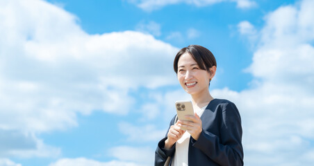 ビジネス女性・青空・スマートフォン