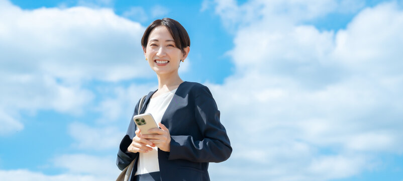 ビジネス女性・青空・スマートフォン