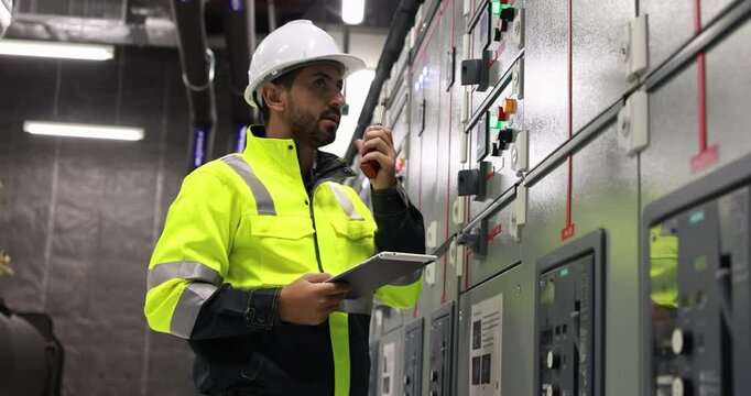 Electrical engineer with green uniform checking and inspecting at MDB panel or Main Distribution Boards of factory