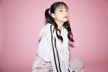 ピンク背景で撮影をしたスポーティな服装をした若い女性のキュートなポートレート