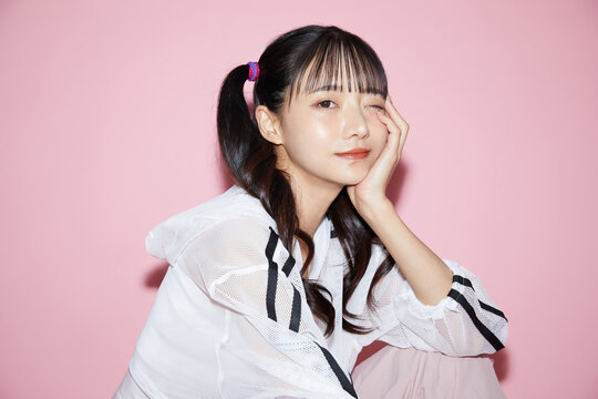 ピンク背景で撮影をしたスポーティな服装をした若い女性のキュートなポートレート