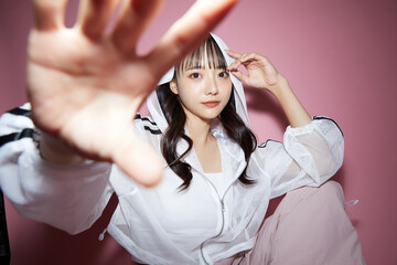 ピンク背景で撮影をしたスポーティな服装をした若い女性のキュートなポートレート