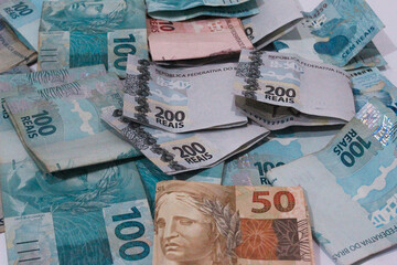 This photographic illustration shows notes of one hundred and two hundred reais and a note of 10 reais. The Real is the current currency in Brazil.