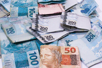 This photographic illustration shows notes of one hundred and two hundred reais and a note of 10 reais. The Real is the current currency in Brazil.