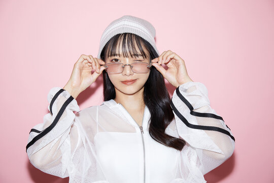 ピンク背景で撮影をしたスポーティな服装をした若い女性のキュートなポートレート