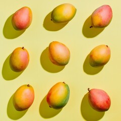 Fresh mangoes arranged on a bright yellow background