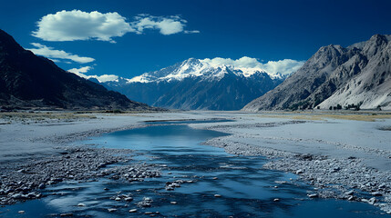 Obraz premium A serene landscape featuring a river surrounded by majestic mountains, clear skies, and rocky terrain, showcasing the beauty of nature