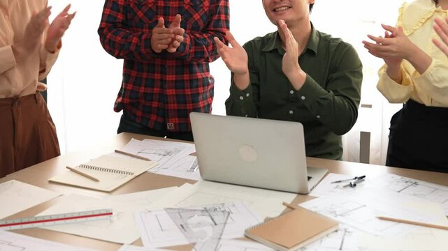 Architect and safety engineer celebrate success design building blueprint project on laptop with architectural document and measurement tool scatter around at modern office. Closeup. Delineation.