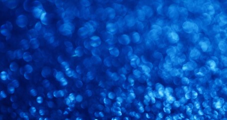 Bokeh sequins. Glittery flare. Decorative festive background with blue blurred chaotic flickering rays delicate fantasy atmosphere.