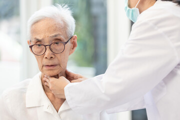 Asian doctor touching throat of an old elderly,problem with thyroid gland,female senior patient...