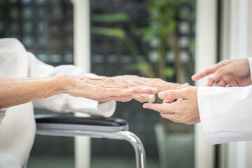 Senior stretching her arms,doctor examines the patient's hands for any tremors,signs of thyroid...