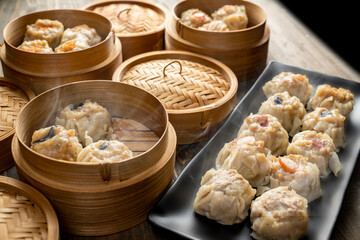 Assorted chinese dim sum dumpling on the plate with bamboo wooden basket bowl on wooden table