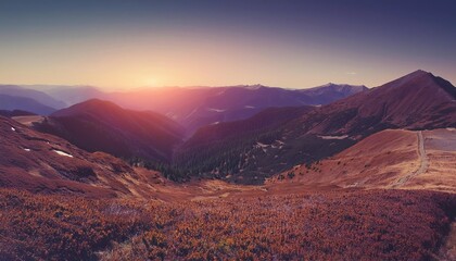 Naklejka premium A panoramic view of mountains at sunrise and sunset with snowy peaks and a vibrant sky