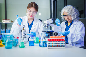 Fototapeta premium Two Asian men and women sit at a table in a laboratory, conducting research on liquids. They use microscopes, petri dishes, and test tubes filled with various chemicals for analysis