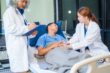 Two female doctors examine a patient lying on a hospital bed,discuss the medical chart,administer...