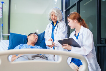 Fototapeta premium Two female doctors examine a patient lying on a hospital bed,discuss the medical chart,administer medicine,and provide encouragement, ensuring compassionate care and fostering the patient's recovery