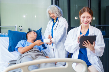 Two female doctors examine a patient lying on a hospital bed,discuss the medical chart,administer medicine,and provide encouragement, ensuring compassionate care and fostering the patient's recovery