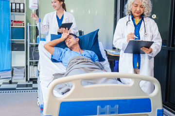 Obraz premium Two female doctors examine a patient lying on a hospital bed,discuss the medical chart,administer medicine,and provide encouragement, ensuring compassionate care and fostering the patient's recovery
