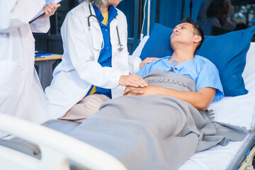 Obraz premium Two female doctors examine a patient lying on a hospital bed,discuss the medical chart,administer medicine,and provide encouragement, ensuring compassionate care and fostering the patient's recovery