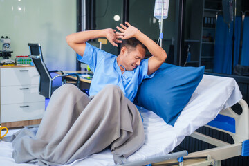 Obraz premium A man with depression sits alone on a hospital bed, feeling stressed, anxious, and bored. He experiences phobia symptoms, including fear, rapid heartbeat, dizziness, sweating, and severe anxiety