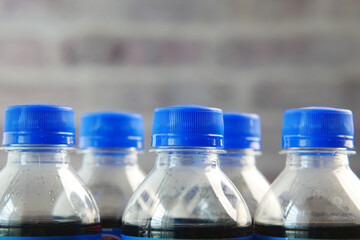 Collection of Bottled Beverages with Blue Caps Set Against a Brick Background