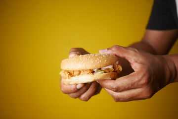 Delicious Handheld Fried Chicken Sandwich on Yellow Background