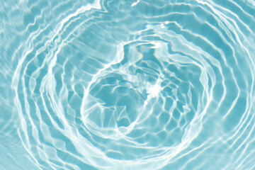 Blue water with ripples on the surface. Defocus blurred transparent blue colored clear calm water surface texture with splashes and bubbles. Water waves with shining pattern texture background.