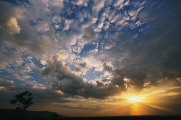 sun burst at sunset with blue sky and white clouds