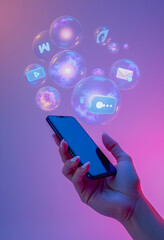Hand holding a phone with social media bubbles.