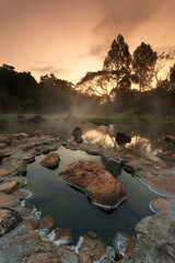 Hot springs over rock terrain with misty and morning sunrise rays and Natural Mineral Water of Chae Son National Park in Lampang Province, Thailand.