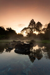 Hot springs over rock terrain with misty and morning sunrise rays and Natural Mineral Water of Chae Son National Park in Lampang Province, Thailand.