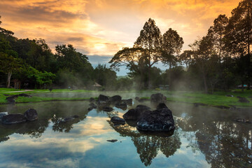 Hot springs over rock terrain with misty and morning sunrise rays and Natural Mineral Water of Chae Son National Park in Lampang Province, Thailand.