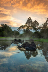 Hot springs over rock terrain with misty and morning sunrise rays and Natural Mineral Water of Chae Son National Park in Lampang Province, Thailand.