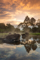 Hot springs over rock terrain with misty and morning sunrise rays and Natural Mineral Water of Chae Son National Park in Lampang Province, Thailand.