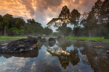 Hot springs over rock terrain with misty and morning sunrise rays and Natural Mineral Water of Chae Son National Park in Lampang Province, Thailand.